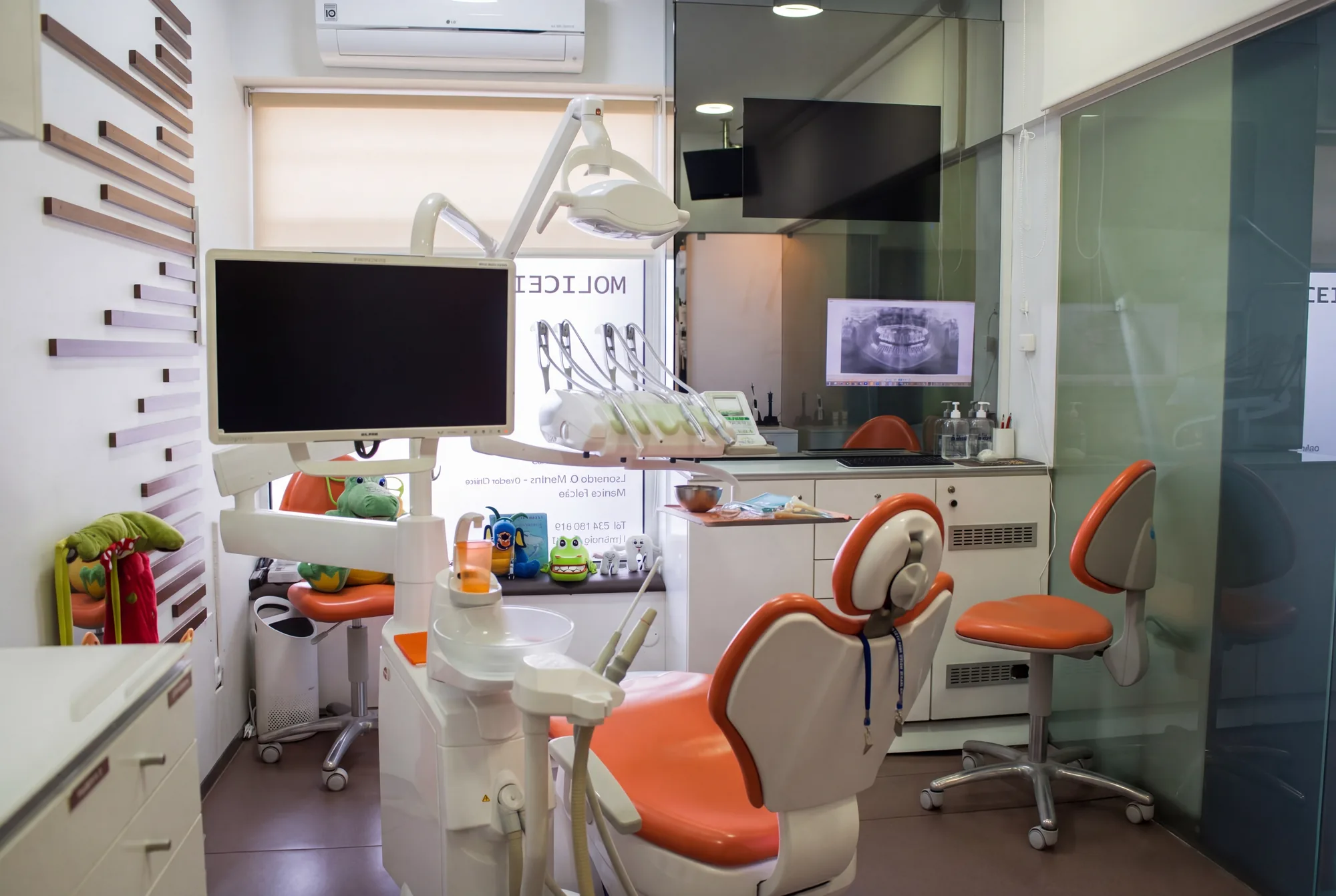 Gabinete infantil da Clínica Moliceiro Oliveira do Bairro, cadeira dental laranja num espaço pensado para crianças